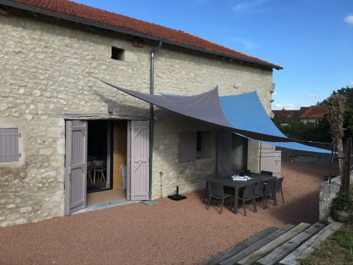 Les Charmises cottage garden patio with shade sails and dining table in Charroux