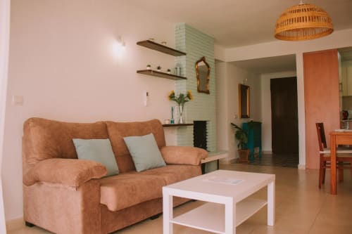 Lumineux séjour avec canapé terracotta, table blanche et cheminée menthe à l'appartement Love Rent4 Málaga à Torremolinos