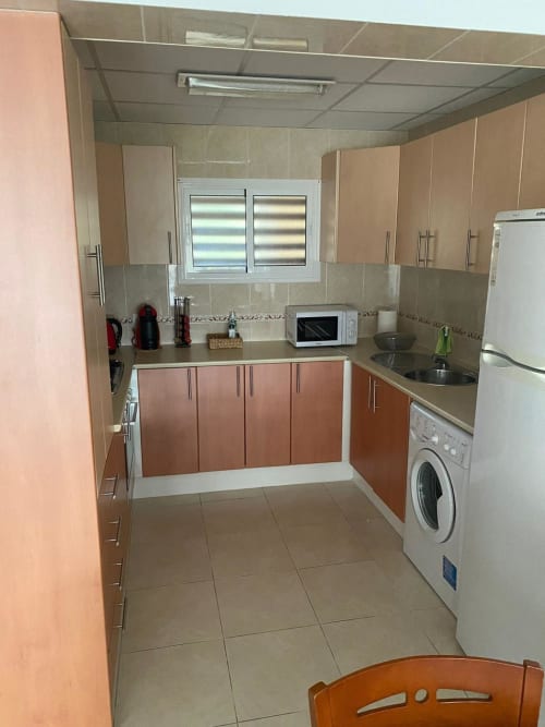 Cuisine moderne de l'appartement Love Rent4 Málaga avec placards en bois, électroménagers blancs et carrelage à Torremolinos