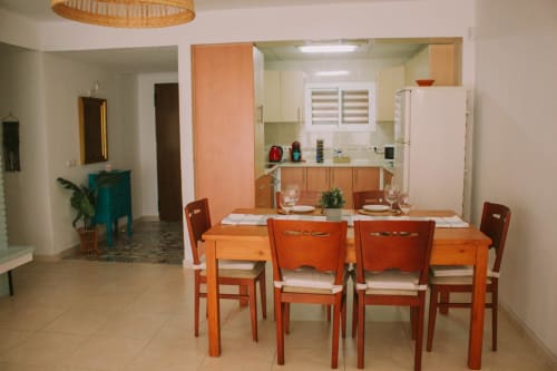 Salle à manger avec table en bois et chaises orange dans un appartement à Torremolinos, vue sur la cuisine et le jardin