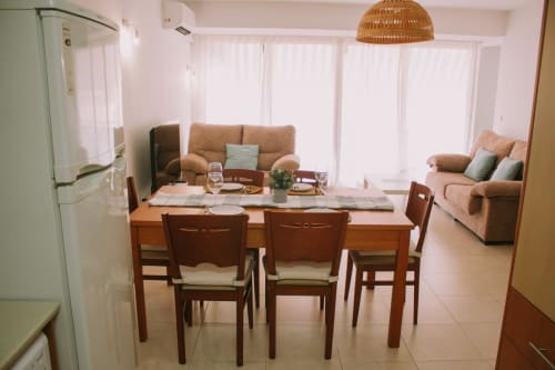 Espace ouvert avec coin repas et séjour dans l'appartement Love Rent4 Malaga, table en bois, canapés beige et vue sur le jardin