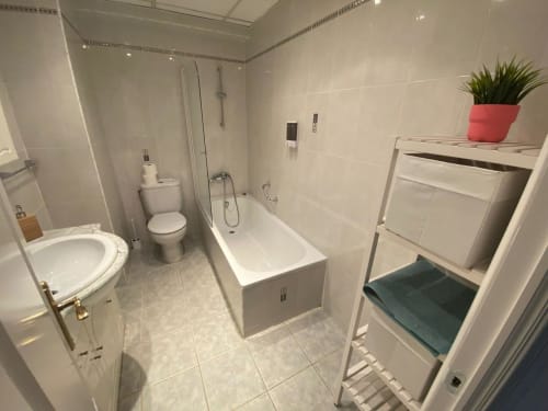 Salle de bain moderne de l'appartement Love Rent4 Málaga avec toilettes, baignoire, douche, lavabo, rangements et plante en pot