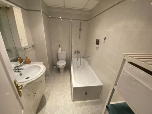 Salle de bain moderne de l'appartement Love Rent4 à Málaga avec vasque blanche, baignoire, toilettes et carrelage à Torremolinos.