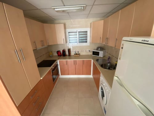 Cuisine moderne de l'appartement Love Rent4 Málaga avec armoires pêche, lave-linge, micro-ondes et appareils blancs