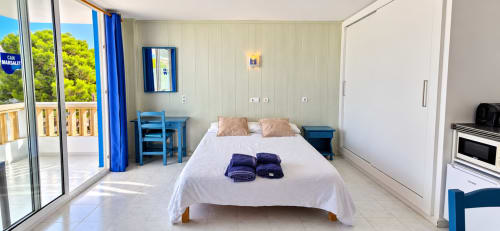 Luminoso dormitorio doble en Can Marsalet, Portocolom, con balcón vista al mar, detalles azules y comodidades modernas