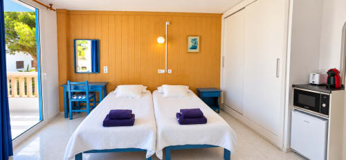 Habitación doble en Apartamentos Can Marsalet, Portocolom: dos camas, mobiliario azul, cocineta y acceso a balcón