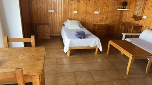 Dormitorio rústico de madera en Apartamentos Can Marsalet, Portocolom, con cama individual, mesa de comedor y mobiliario tradicional
