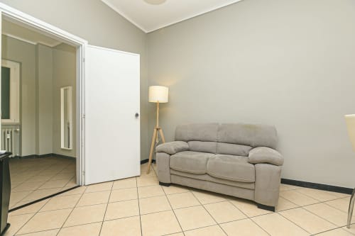 Moderno soggiorno dell'appartamento Rosa House a Genova con divano beige, lampada a stelo e pavimento in cotto