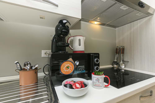 Piccola cucina della Rosa House con caffettiera, microonde, pentole e accessori per mangiare a Genova