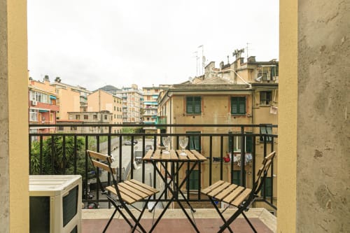 Balcone dell'appartamento a Genova con vista sulla città, sedie in legno e piastrelle in terracotta che si affacciano su edifici storici