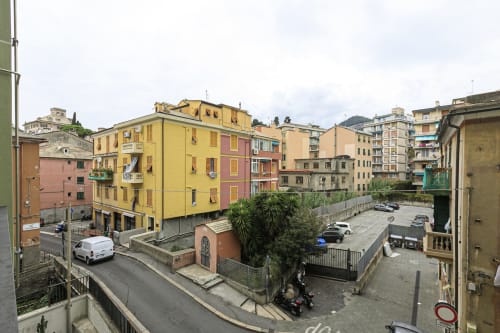 Edifici residenziali colorati nel centro di Genova con auto parcheggiate e palme, vista dell'appartamento Rosa House