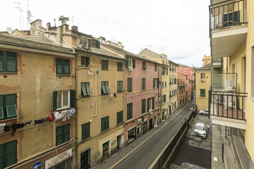 Edifici colorati su una strada stretta a Genova, con persiane verdi e bucato sui balconi
