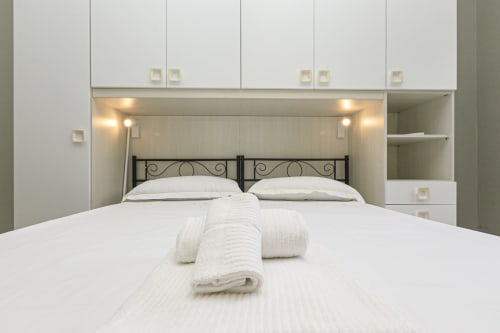 Camera da letto moderna nell'appartamento Rosa House a Genova, con armadi a muro bianchi, letto in metallo nero e biancheria bianca