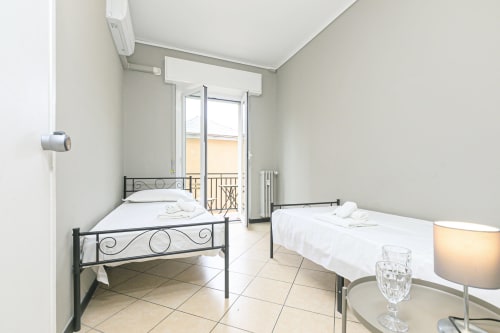 Camera luminosa a Genova con due letti singoli, balcone con vista città e comfort moderni