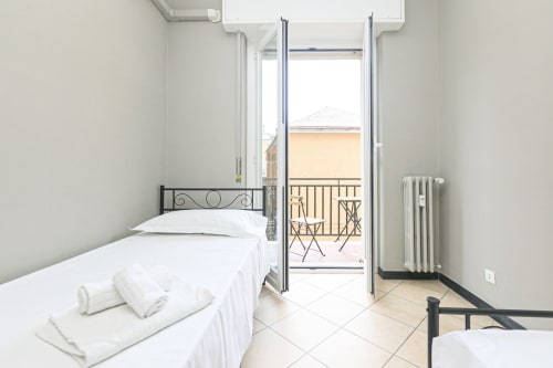 Camera luminosa della ML White House a Genova con letto gemello, balcone aperto, vista sulla città e comfort moderni