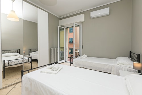 Camera moderna nell'appartamento Rosa House a Genova con letti gemelli, armadio con specchio, balcone con vista sulla città e aria condizionata