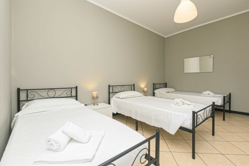 Tre letti singoli con biancheria bianca in una luminosa camera da letto dell'appartamento presso ML White House, Genova, con arredi moderni e vista città