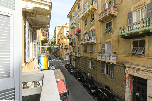 Vista dal balcone di Genova con edifici storici gialli colorati e auto parcheggiate, Appartamento Narciso House