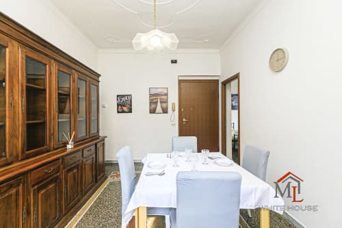 Elegante sala da pranzo nell'appartamento Narciso House a Genova, con mobile in legno, tavolo vestito di bianco e vista sulla città