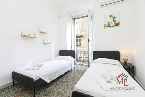Letti gemelli con testiera nera nell'appartamento Narciso House presso ML White House a Genova, con balcone vista città e stile nautico
