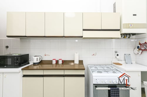 Cucina moderna nell'appartamento Narciso House a Genova con ante color crema, fornello a gas, microonde e piano di lavoro in legno