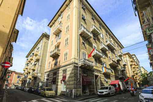 Edificio residenziale giallo all'angolo di via Genova con tende rosse, vista sulla città da Narciso House