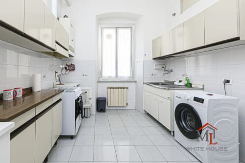 Cucina moderna dell'appartamento ML White House a Genova con mobili bianchi, elettrodomestici, lavatrice e pavimentazione piastrellata