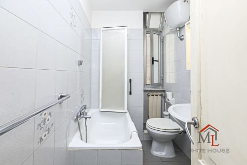 Bagno moderno nell'appartamento Narciso House a Genova, con piastrelle bianche, vasca con doccia, WC e riscaldamento