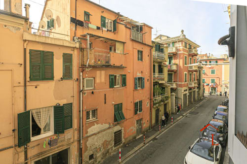 Edifici residenziali colorati a Genova con persiane verdi, balconate e scooter parcheggiato, vista cittadina
