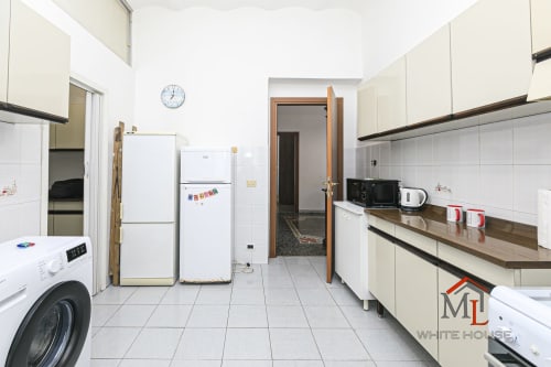 Ampia cucina nell'appartamento Narciso House presso ML White House, Genova, con cabinetry bianca e ripiani in marrone