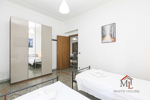 Camera da letto dell'appartamento Narciso House a Genova con due letti, armadio con specchio e vista sulla città
