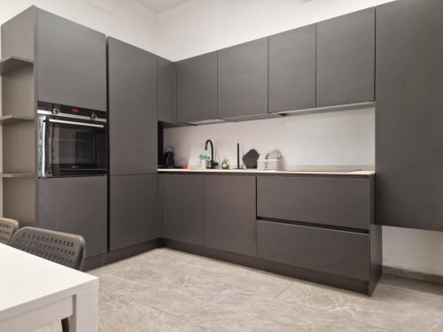Cucina moderna grigio scuro con piano lavoro bianco, forno incassato e lavello nell'appartamento Fresia House, hotel Genova.