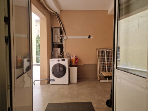 Moderna lavanderia nell'appartamento Fresia House a Genova, con lavatrice bianca, muri arancioni e vista sulla città
