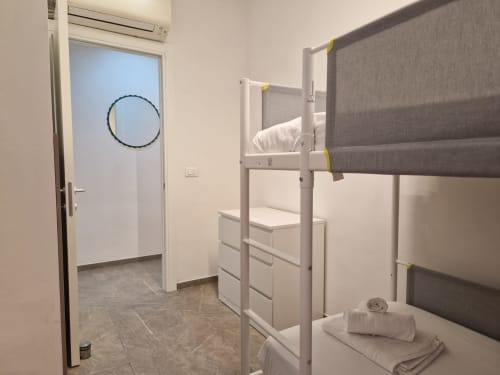 Camera dormitorio moderna con letti a castello bianchi e grigi, cassetti per riporre e accesso al bagno interno privato presso ML White House