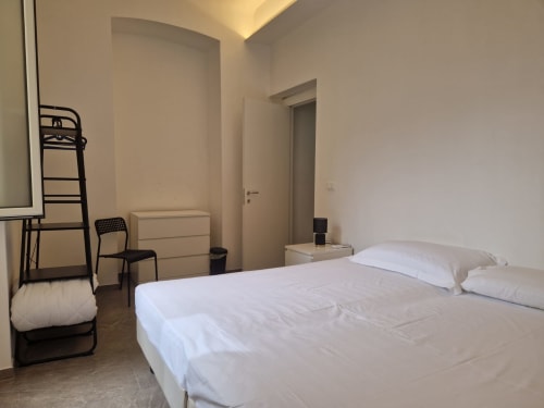 Camera da letto moderna a Genova con letto bianco, scrivania e libreria a scala in design minimalista