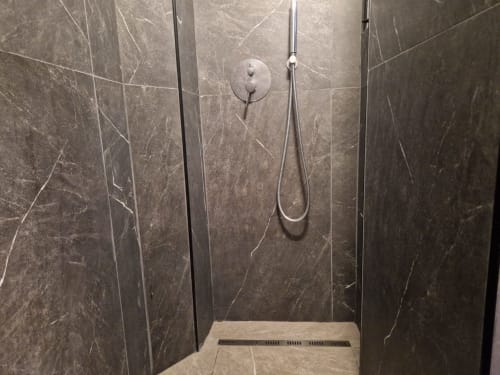 Moderno box doccia con piastrelle in marmo nero e finiture cromate nell'appartamento ML White House a Genova