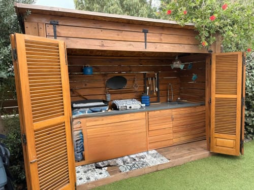 Cuisine extérieure en bois avec plan de travail inox, grill à gaz et touches bleues aux Villas d'A Storia
