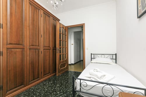 Camera da letto nell'appartamento GELSOMINO HOUSE a Genova con armadio in legno, letto singolo e vista sulla città