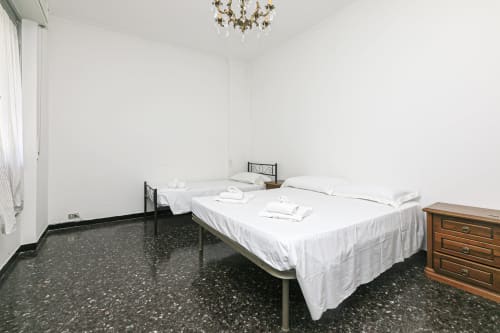 Camera luminosa della CASA GELSOMINO, appartamento a Genova con letto matrimoniale, letto singolo, cassettone in legno e pavimento in terrazzo