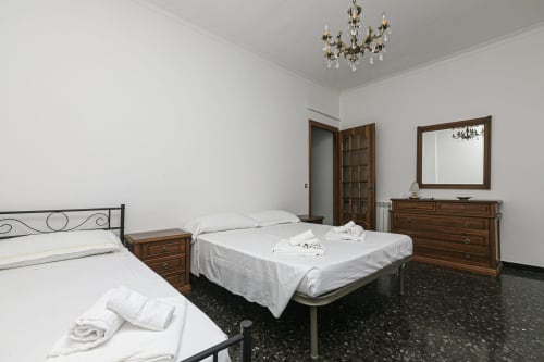 Camera spaziosa a Gelsomino House a Genova con due letti, mobili in legno, lampadario e vista sulla città