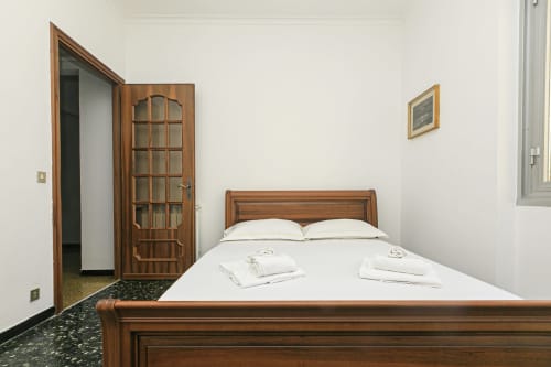 Camera da letto con letto in legno, biancheria bianca e armadio nell'appartamento Gelsomino House, Genova