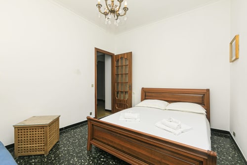 Camera da letto in Gelsomino House, Genova: letto in legno, biancheria bianca e vista sulla città