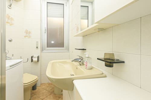 Bagno pulito con lavandino, wc e piastrelle bianche nell'appartamento Gelsomino House, Genova