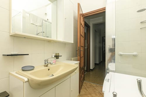 Bagno moderno nell'appartamento Gelsomino House a Genova con lavabo color crema, mobile con specchio e box doccia