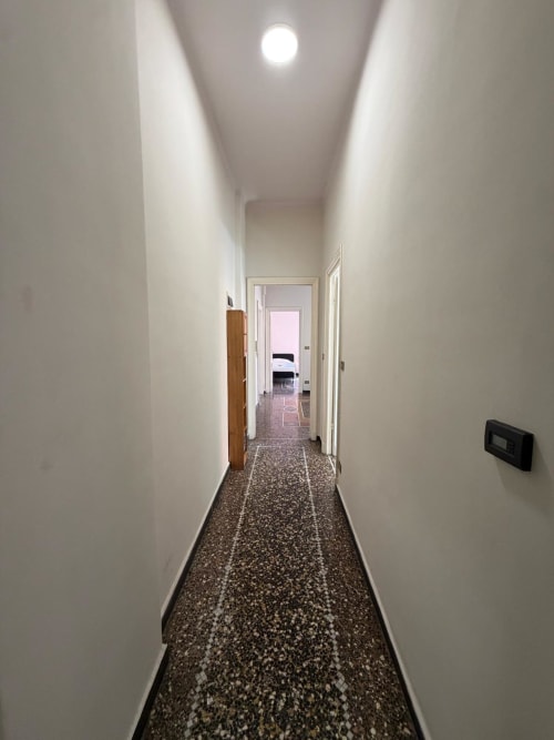Corridoio moderno e stretto con pareti bianche e pavimentazione in terrazzo nell'appartamento Tulipano House, Genova