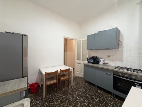 Cucina e zona pranzo moderna dell'appartamento Tulipano House a Genova, con mobili grigi, fornello a gas e sedie in legno