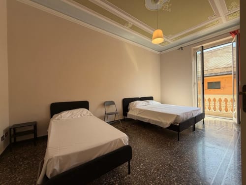 Due letti singoli con biancheria bianca in luminoso appartamento a Genova con balcone vista città