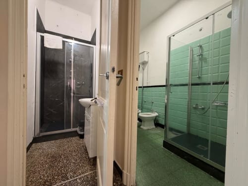 Due moderne cabine doccia con box in vetro presso l'appartamento Tulipano House a Genova, con piastrelle verdi e