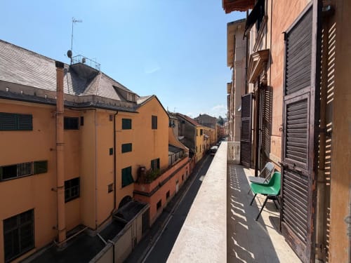 Balcone soleggiato con vista su stretto vicolo di Genova circondato da edifici arancioni, appartamento ML White House