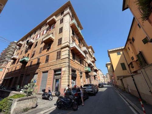 Veduta di strada a Genova con edifici residenziali in terracotta e parcheggio cittadino, location ML White House